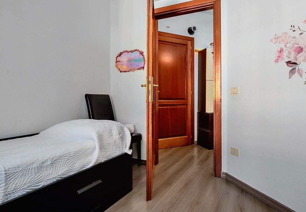 A bedroom with a bed, a wooden door, and a wall decoration.