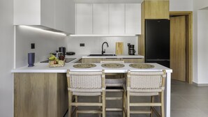 Eine moderne Küche mit weißen Schränken, einem schwarzen Kühlschrank, einer Holztür und einer Bar mit gewobenen Stühlen.