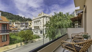Ein Balkon mit Korbstühlen, Blick auf eine Straße und Gebäude im Hintergrund.