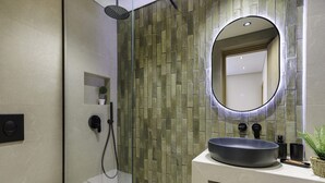 Ein modernes Badezimmer mit einer Duschkabine aus Glas, einem runden Spiegel und einem Waschbecken mit einer Haube.