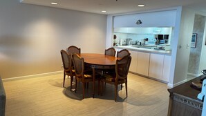 A dining area with a wooden table and wicker chairs, a kitchen with white cabinets, and a tiled floor. - Charming 2-bedroom condo with AC, fitness room in wonderful Longboat Key (Longboat Key)