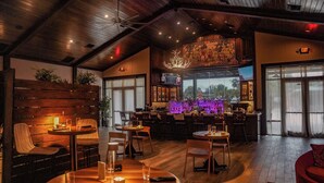 A restaurant with wooden furniture, a bar area, and large windows. - Black Prong Resort (Bronson)