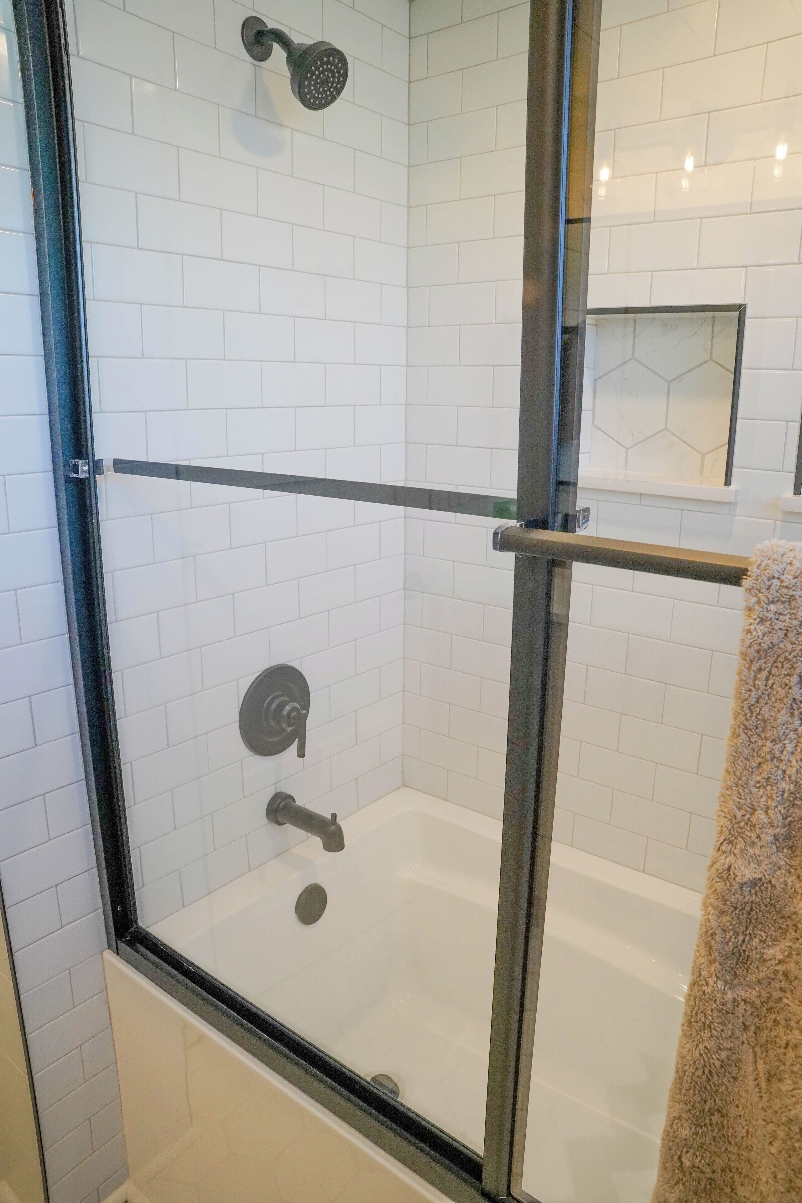 A glass-enclosed shower with white tiled walls and a glass door.
