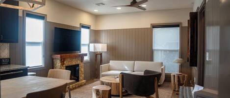 A modern living room with a fireplace, a sofa, a dining table, and a TV.