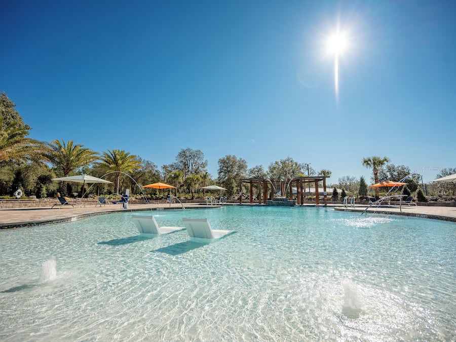 Una piscina al aire libre, sombrillas, sillones reclinables de piscina