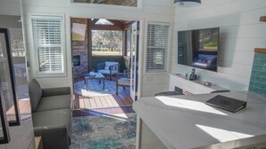 A modern kitchen with a built-in TV, a dining area with outdoor seating, and a view of the patio. - Black Prong Resort (Bronson)