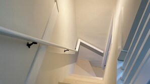 A staircase with white walls and a wooden floor, leading to an upper level. - Charming Apt above Bookshop in Historic Tiverton Four Corners Village Center! (Tiverton)