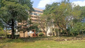 A building with a modern architectural style, surrounded by a well-maintained garden with various trees and a stone pathway.