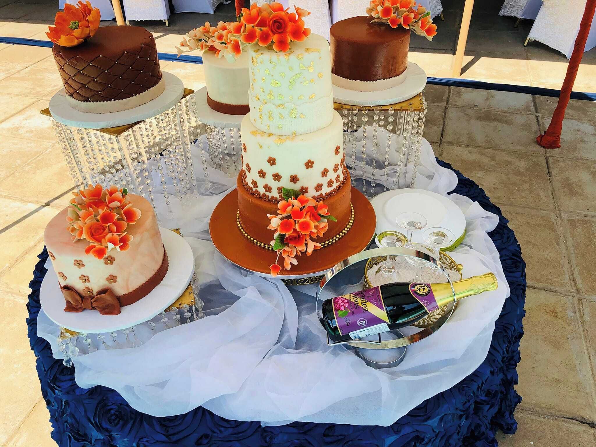 A table with three tiered cakes, a bottle of champagne, and a glass.