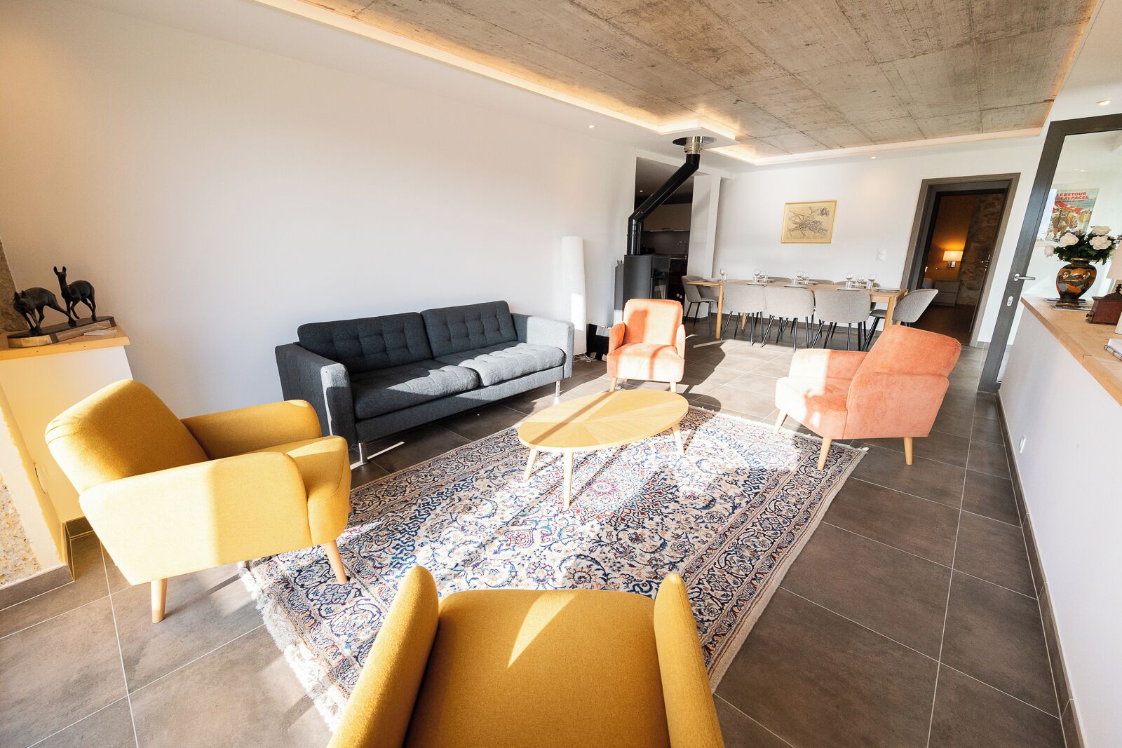 Un salon moderne avec un canapé, deux fauteuils, une table basse et un tapis à motifs.