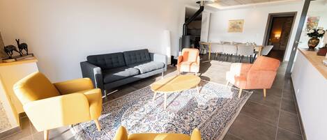 Un salon moderne avec un canapé, deux fauteuils, une table basse et un tapis à motifs.