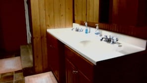 Une salle de bain avec un meuble-lavabo en bois, un lavabo blanc et un miroir au-dessus.