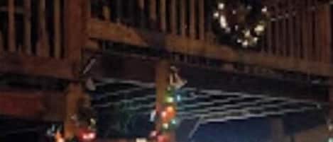 A wooden deck with railings and a sign, decorated with string lights and a wreath.