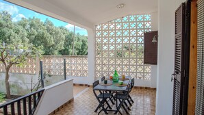 A balcony with a tiled floor, a table with chairs, and a decorative fence. - Villa Ada (Leporano Marina)