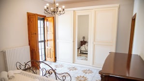 A bedroom with a bed, a dresser, a radiator, and a chandelier. - Villa Ada (Leporano Marina)