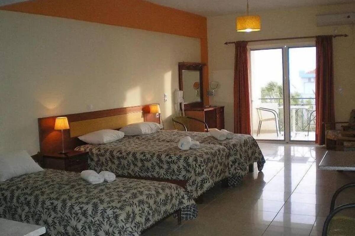 A hotel room with two beds, a desk, a chair, and a balcony.