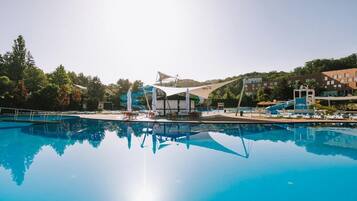 Una piscina con vistas despejadas del entorno, incluyendo un tobogán acuático y un edificio de techo inclinado.