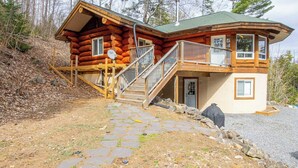 A log cabin with a stone pathway leading to a wooden staircase and a deck. - Timber Wilderness Lodge (North Frontenac)