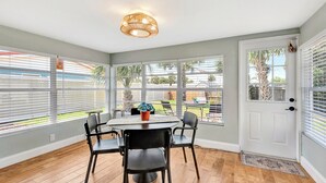 Un coin repas avec une table ronde, quatre chaises et un luminaire suspendu au plafond.