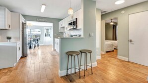 Une cuisine moderne avec des meubles blancs, un îlot central et deux tabourets de bar.