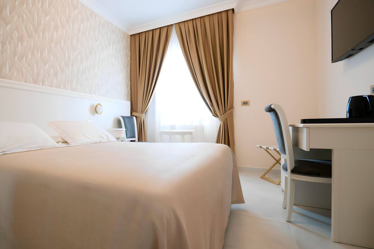 Una habitación de hotel con una cama grande, un escritorio, una silla y un televisor.