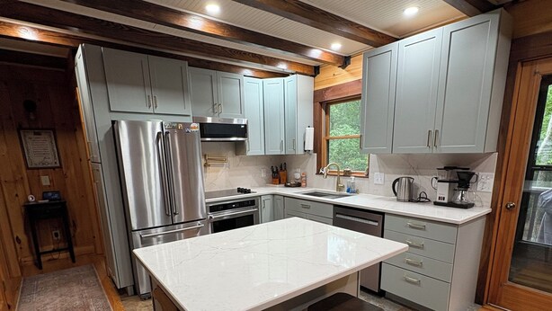 A modern kitchen with a central island, stainless steel appliances, and wooden flooring.