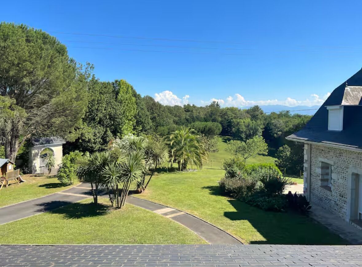 Una propiedad residencial con entrada pavimentada, césped y vista a un área boscosa.