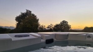 A hot tub with a view of trees and mountains in the background.