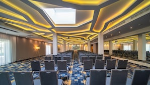 A conference room with rows of chairs, a patterned carpet, and a skylight. - Green Garden Hotel (Falenty)