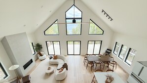 Un loft spacieux avec de hauts plafonds, de grandes fenêtres, un coin repas et un espace salon confortable.