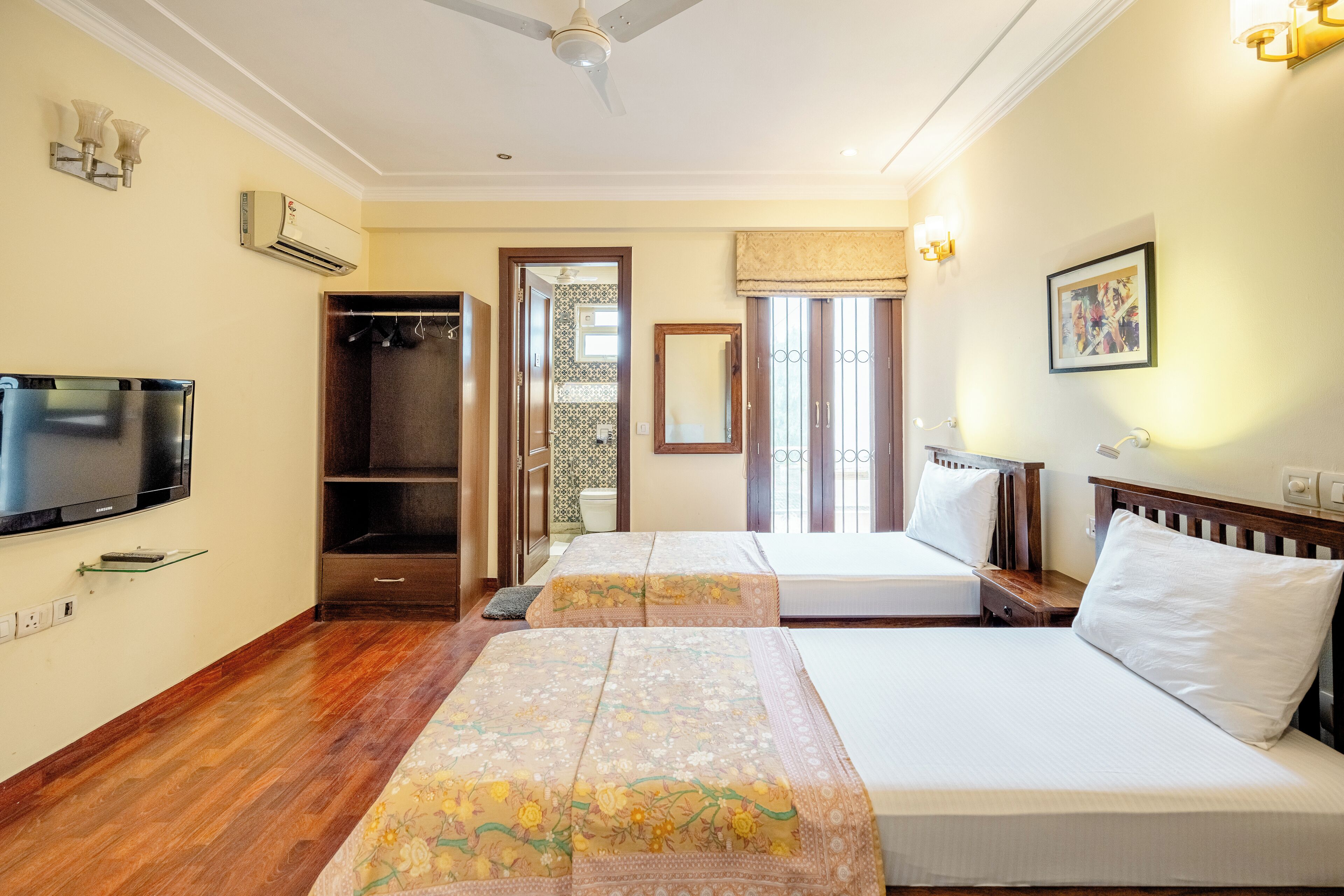 Une chambre d’hôtel avec deux lits, une télévision, un appareil de climatisation et une armoire.