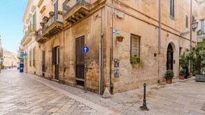 A historic building with a stone facade, multiple windows, and a sign indicating a courtyard. - Suite Corte Volturio by BarbarHouse (Lecce)