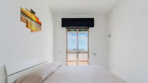 Un dormitorio con cama, ventana y vistas al exterior.