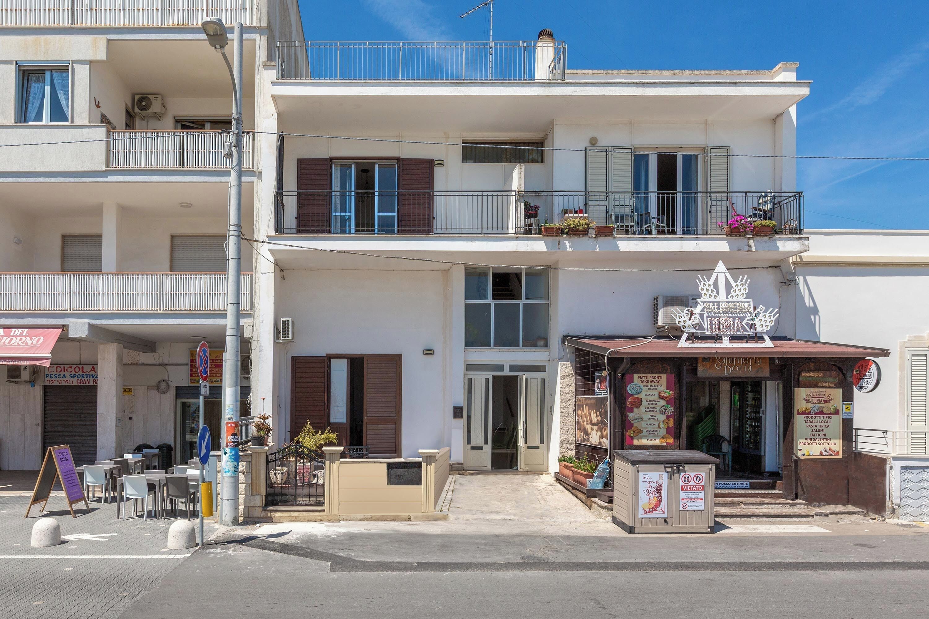A two-story building with a restaurant on the ground floor and a balcony with potted plants.
