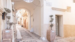 A narrow cobblestone street with buildings on either side, a sign for 'Kastelle Restaurant', and potted plants along the path. - Villa Helena by BarbarHouse (Vieste)