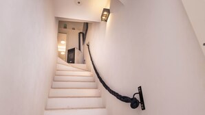 A staircase with a black rope handrail and a wall-mounted light fixture. - Villa Helena by BarbarHouse (Vieste)