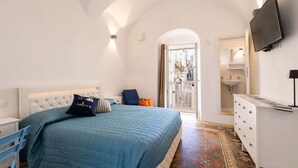 A bedroom with a bed, a dresser, a TV, and a bathroom visible through an open door. - Villa Helena by BarbarHouse (Vieste)