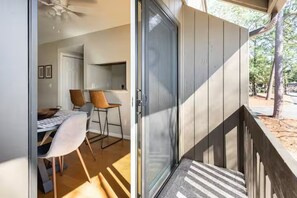 Een modern interieur met een eethoek, een schuifdeur naar een terras en uitzicht op de omliggende bomen.