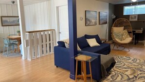 A living room with a blue sofa, a wooden coffee table, a wicker chair, and a patterned rug. - Large, fully-equipped apartment - private access (ideal for visiting Quebec City) (Lévis)