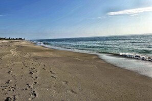 A beach with footprints leading to the water, a clear sky, and a calm sea. - Walk to Beach, Dining, Shops, Screen Patio, Game Room, Hobe Sound Zeus Park (Hobe Sound)