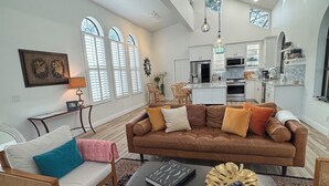 A spacious living room with a brown leather sofa, a coffee table, and a patterned rug. - Walk to Beach, Dining, Shops, Screen Patio, Game Room, Hobe Sound Zeus Park (Hobe Sound)