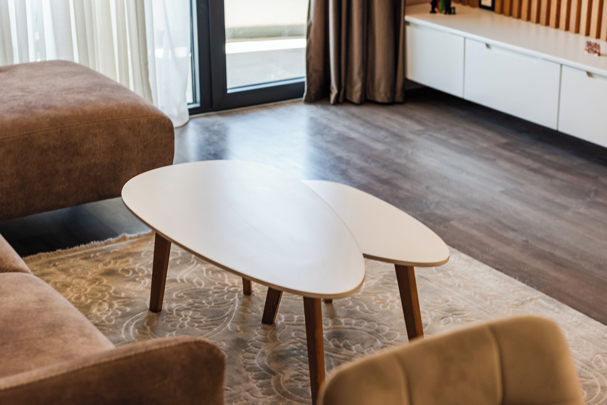 Un salon moderne avec un canapé, une table basse et une vue sur l’extérieur grâce à une grande fenêtre.