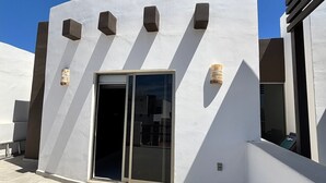 Un bâtiment moderne à l’extérieur blanc, doté d’une porte d’entrée en verre et d’un patio carrelé.