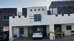 Un bâtiment moderne à la façade blanche, avec une voiture garée devant et une allée pavée.
