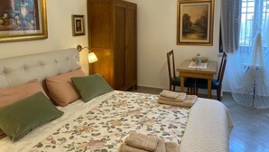 Une chambre à coucher avec un lit, une armoire en bois, un bureau avec une chaise et deux tableaux accrochés au mur.