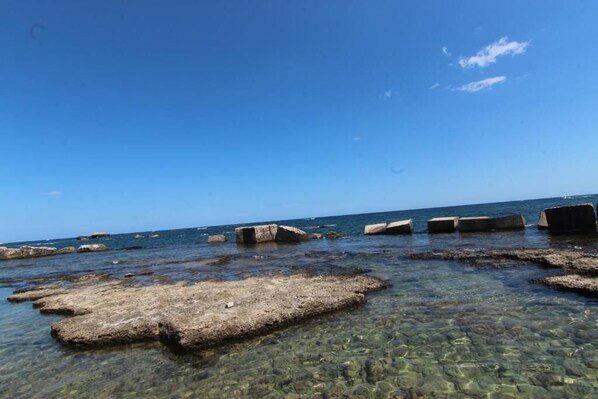 A rocky shoreline with clear water and a clear sky.