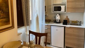 Une cuisine compacte équipée d’un four à micro-ondes, d’une machine à café, d’un évier et d’un petit réfrigérateur.