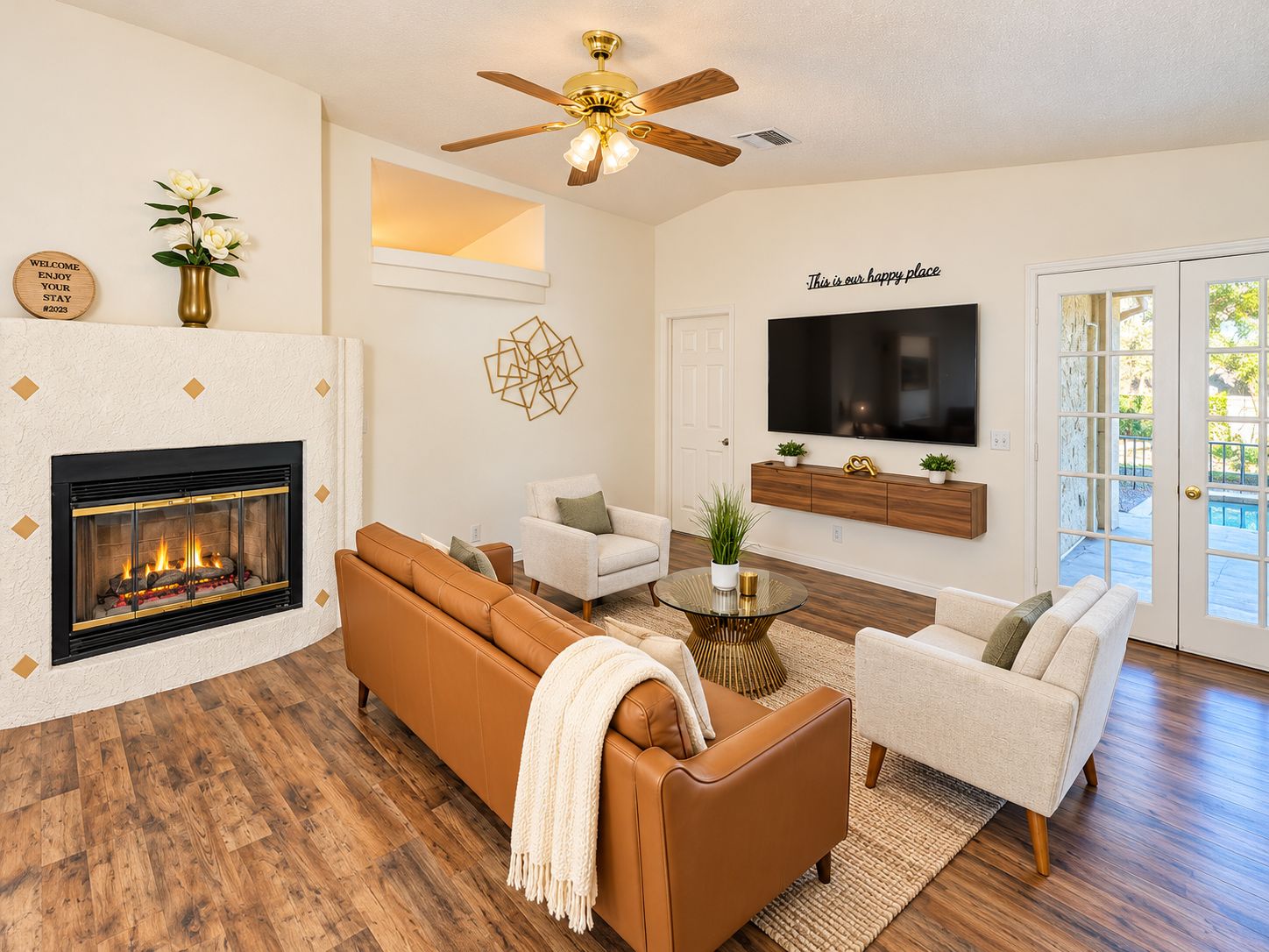 A living room with a fireplace, a sofa, a television, and a ceiling fan.