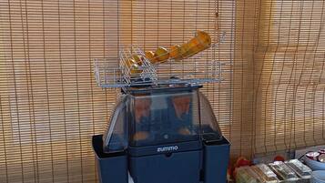 A food service station with a grill, a juicer, and a tray of food items.