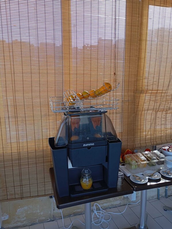 A food service station with a grill, a juicer, and a tray of food items. - Villa Del Porto (Kalkara)